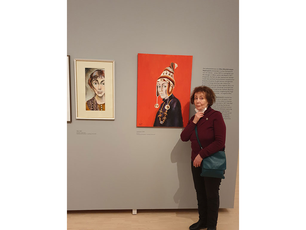 NinaWR in front of the two self-portraits with MNS mask for a moment under her chin